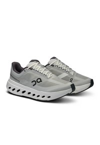 Baskets de sport gris clair avec une tige en maille texturée et des accents noirs contrastants. Présentent une semelle épaisse et rembourrée avec un design découpé.