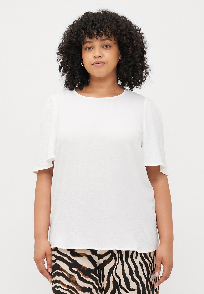 White short-sleeve top with a smooth texture and a round neckline, paired with patterned pants featuring black and brown zebra stripes.
