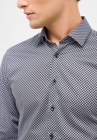 Zwart-witte gestreepte blouse met een aangebrachte kraag, met een ruitpatroon en zwarte knopen. Close-up uitzicht op de textuur van de stof.