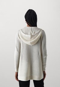 Bílý, lehký, mikina s kapucí s otevřeným pletením, dlouhými rukávy, žebrovanými manžetami a lemem; uvolněný střih.