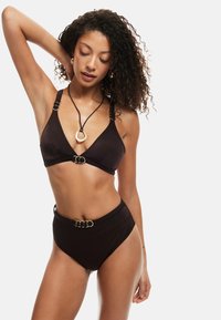 Conjunto de bikini negro que incluye un bralette triangular con detalles en dorado y una parte inferior de tiro alto con un detalle de hebilla dorada a juego.