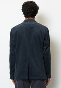 Blazer in velluto a coste blu navy con rigatura verticale, spacchetto singolo sul retro, vestibilità sagomata e chiusura a due bottoni. Vista posteriore che mette in evidenza la trama.