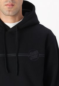 Svart hoodie av bomull med dragsko i huvan, diskret logotyp i grått och en minimalistisk horisontell randdesign.