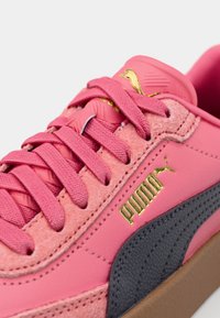 Rosa sneaker med texturerad ovandel, med en grå rand och guldiga logotypdetaljer. Gummisula och matchande rosa snören fulländar designen.