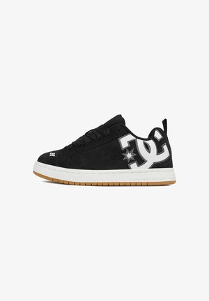 Sneaker basso nero con logo DC bianco e grigio sul lato, lacci neri, suola bianca e battistrada color gomma su sfondo bianco.