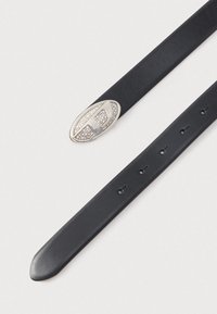 Melnas ādas josta ar ovālu sudraba sprādzi, rotātu ar nelieliem skaidriem kristāliem, ar vairākiem regulēšanas caurumiem.