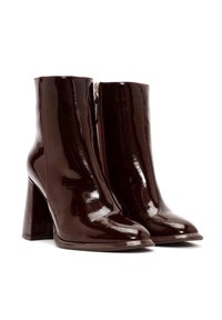 Bottines en cuir verni marron avec un haut talon bloc, bout pointu et fermeture éclair latérale, présentant une finition lisse et brillante.