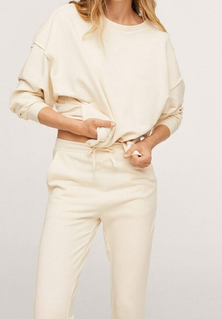 Conjunto de ropa de descanso beige claro que incluye una parte superior de manga larga de corte holgado y pantalones jogger ajustados en el tobillo, ambos hechos de tela suave para mayor comodidad.