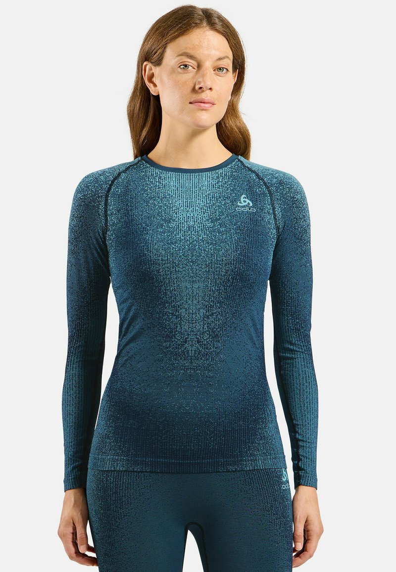 Dames lange mouwen sporttop in donkerblauwgroen met een textuurpatroon en ribbelontwerp, met een ronde halslijn en een logo-detail op de borst.