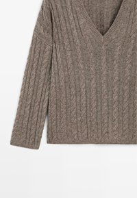 Pullover marrone a maglia con scollo a V, caratterizzato da un motivo a trecce, maniche lunghe e polsini a costine, realizzato in materiale morbido e testurizzato.