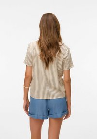 Chemise rayée beige à manches courtes, assortie à un short bleu clair avec un ourlet festonné. Les tissus semblent légers et décontractés.