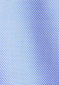 Tissu à motifs en zigzag bleu et blanc avec un petit motif chevron répétitif montré en gros plan.