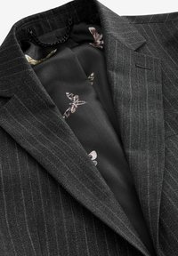 Grahamfarbener Blazer mit Nadelstreifen und strukturiertem Stoff; das Innenfutter zeigt ein florales Muster in dunklen Farbtönen. Inklusive Aufhängeöse.