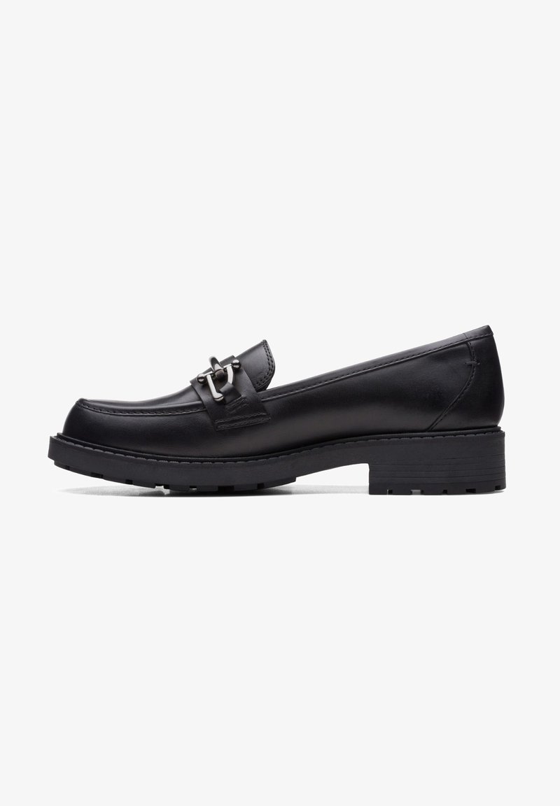 Mocassin en cuir noir avec petit talon carré et détail en métal sur le cou-de-pied, présentant des accents cousus et une semelle en caoutchouc robuste.