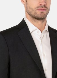 Schwarze maßgeschneiderte Sakkos mit glatter Textur und scharfen Revers, kombiniert mit einem weißen Hemd mit Kragen und Knopfdetails.
