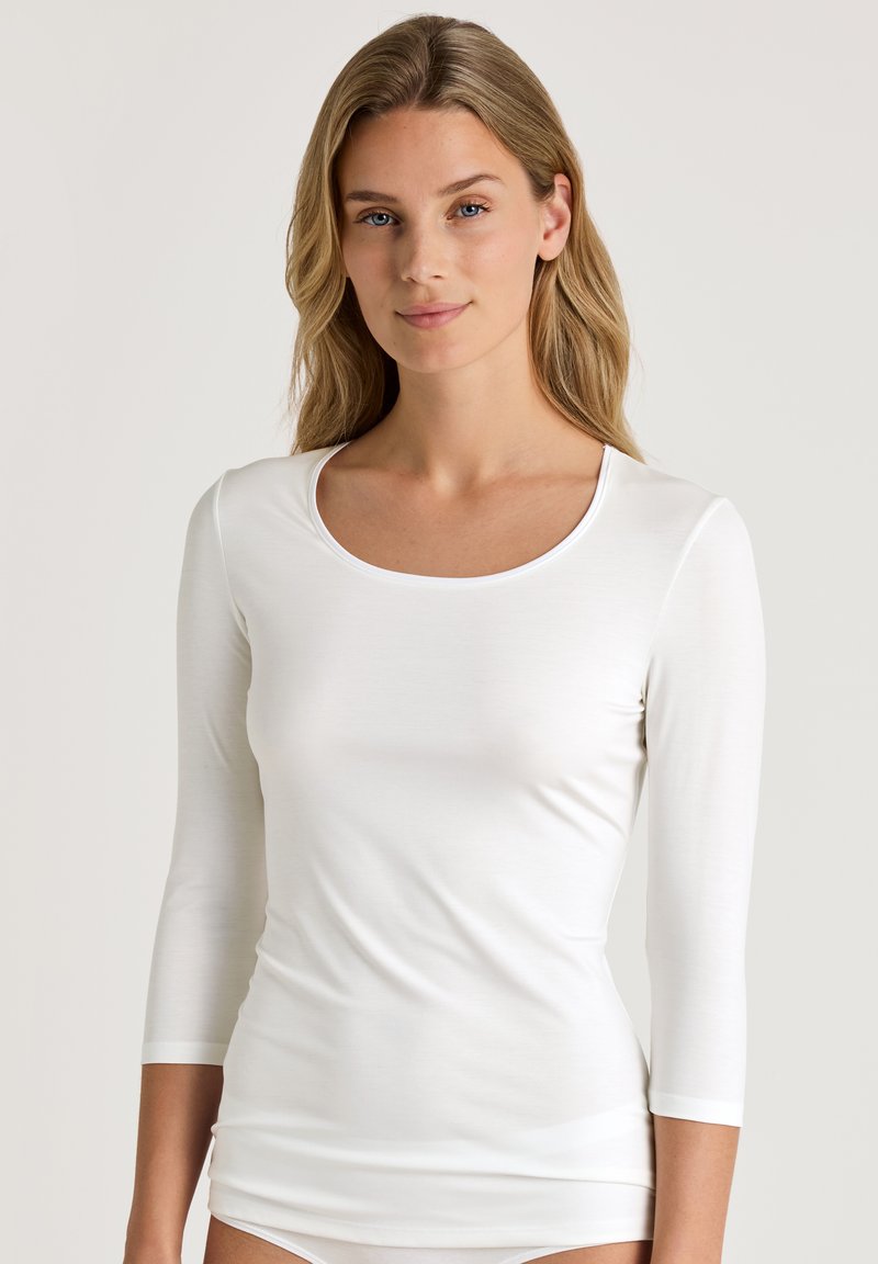 Witte blouse met lange mouwen, voorzien van een ronde hals, zachte textuur en aansluitende pasvorm, ideaal voor het dragen in lagen of casual gebruik.