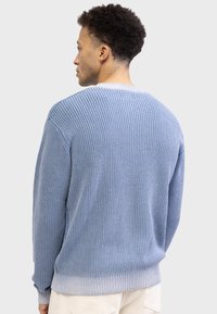 Blue knit sweater with ribbed texture, featuring a contrasting light blue hem. Wide round neckline and long sleeves.