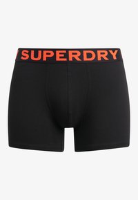 Boxer-briefs noirs avec une large ceinture arborant un audacieux texte orange "SUPERDRY". Fabriqués en tissu lisse et extensible avec un design ajusté.