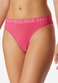 Růžové tangové spodní prádlo s hladkým, elastickým materiálem. Má široký kontrastní pás, na kterém je bílými písmeny vytištěno jméno značky "ELLE".