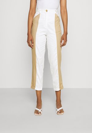 Hoge taille broek van witte hoofdstof met tan zijkanten. Beschikt over een knoopsluiting en opgerolde mouwen. Glad van textuur.