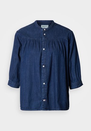 Camicia di denim blu scuro, con collo alto, chiusura frontale con bottoni e dettagli arricciati sulle spalle. Maniche lunghe a sbuffo.