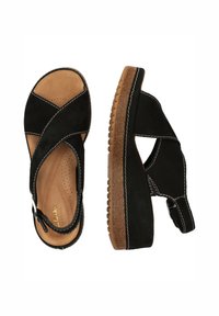 Svarta mockaskor med korsbanddesign, tan dämpad innersula och texturerad gummiyttersula med synliga sömnadsdetaljer.