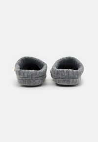 Chaussons gris tricotés avec un design texturé, arrière arrondi et intérieur doux. Style minimaliste sans éléments métalliques visibles ni accents.