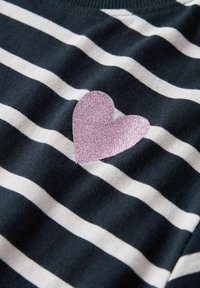 Schwarz-weiß gestreifter Stoff mit einer glitzernden pinkfarbenen Herz-Applikation auf der linken Seite, die eine weiche Textur und ein lässiges Design zeigt.