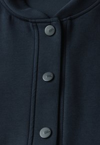Felpa blu navy con collo tondo, dotata di quattro bottoni a pressione neri e cuciture piatte. Realizzata in tessuto morbido e texturizzato.