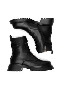 Schwarze Leder-Stiefeletten mit Schnürung vorne, seitlichem Reißverschluss und einer dicken Gummisohle mit ausgeprägtem Profil.