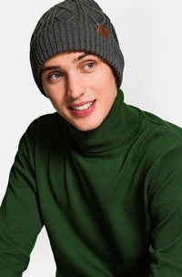 Szary prążkowany beanie z dzianiny ze skórzaną metką, noszony z ciemnozielonym swetrem polo, charakteryzującym się gładką teksturą i dopasowanym krojem.