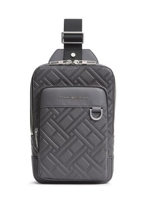 Kompakt sort crossbody taske med præget geometrisk mønster, lynlåslomme foran, metal D-ring og Tommy Hilfiger-logo på forsiden øverst.