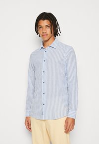Camisa de manga larga a rayas en azul claro y blanco con cuello abotonado y botones azules, hecha de una tela suave. Presenta un dobladillo curvado.