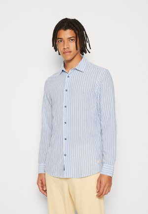 Camisa de manga larga a rayas en azul claro y blanco con cuello abotonado y botones azules, hecha de una tela suave. Presenta un dobladillo curvado.