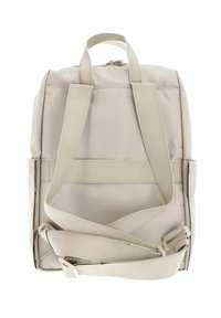 Sac à dos en tissu beige avec des bretelles réglables, une poignée supérieure et une fermeture éclair. Présente une surface texturée et des coutures renforcées.