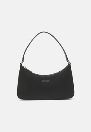 Czarna torba na ramię Calvin Klein z pojedynczym paskiem i górnym zamkiem błyskawicznym, prezentowana na jednolitym białym tle.