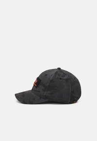 Gorra de béisbol de camuflaje gris oscuro con visera curva y parche de logo naranja en el frente contra un fondo blanco.