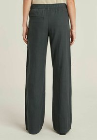 Pantaloni a gamba larga in tessuto grigio scuro, con vita elasticizzata, una tasca posteriore e una superficie liscia. Progettati per comfort e versatilità.