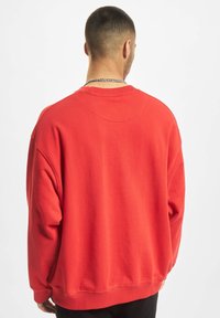 Rode sweatshirt met een relaxte pasvorm, geribbelde manchetten en tailleband. Zacht materiaal met een gladde textuur, met een ronde halslijn en drop shoulders.