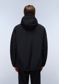 Svart huva jacka med en mjuk yta, avslappnad passform och något elastisk nederkant. Har en enkel design utan dekorationer.