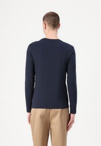 T-shirt a maniche lunghe blu navy realizzata in tessuto morbido, con colletto rotondo e un design semplice, con un accento marrone all'orlo.