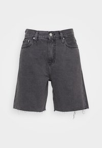 Černé džínové šortky s vysokým pasem, pěti kapsami a roztrhanými lemy. Materiál je pevný s texturovaným povrchem.