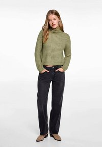 Grön randed polotröja med kort design, ihop med högmidjade svarta vida jeans och beige anklarstövlar.