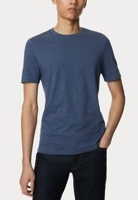 Modré tričko s kulatým výstřihem a krátkým rukávem, vyrobené z jemné texturované tkaniny, spárované s tmavými džíny. Jednoduchý, přiléhavý design bez vzorů.