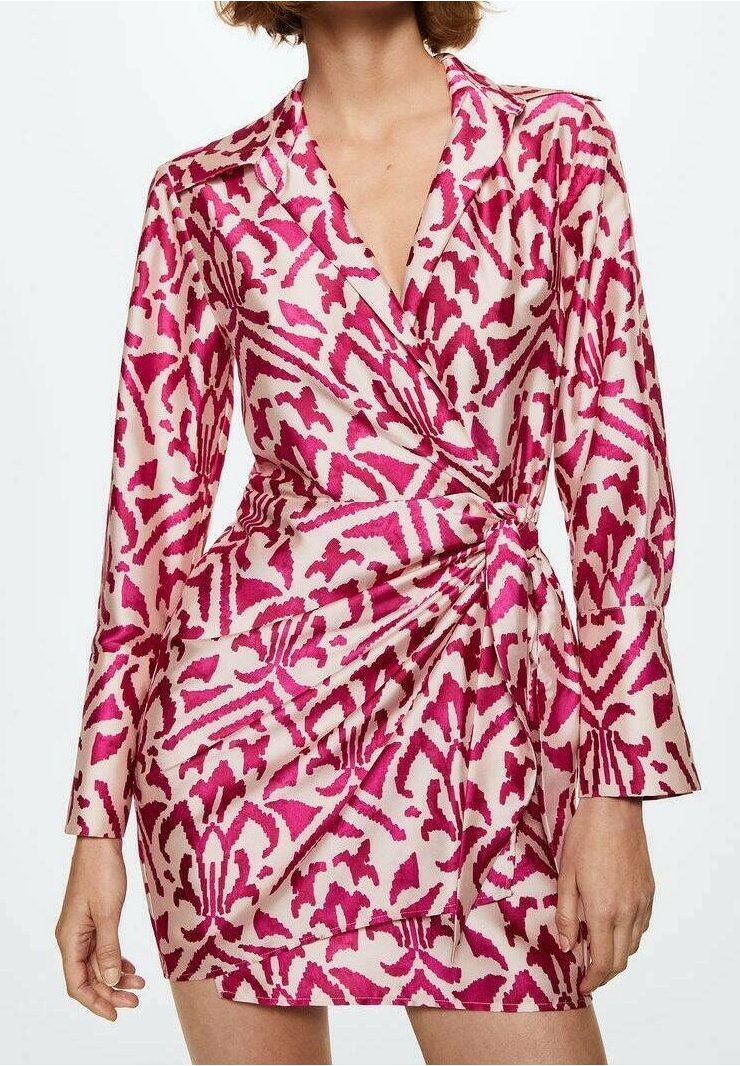 Mujer vistiendo un vestido envolvente de patrón rosa y blanco con mangas largas y un escote en V profundo, que muestra una longitud hasta el muslo y un detalle de cintura fruncida.