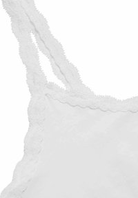 Biała koszulka na ramiączkach z delikatną koronką przy dekolcie i regulowanymi ramiączkami, wykonana z miękkiej bawełny o gładkiej fakturze.