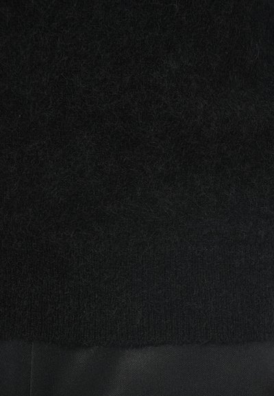 Črn puhast pulover, izdelan iz mehke teksturirane tkanine z rebrastim pletenjem na vrhu in gladkim materialom na dnu.