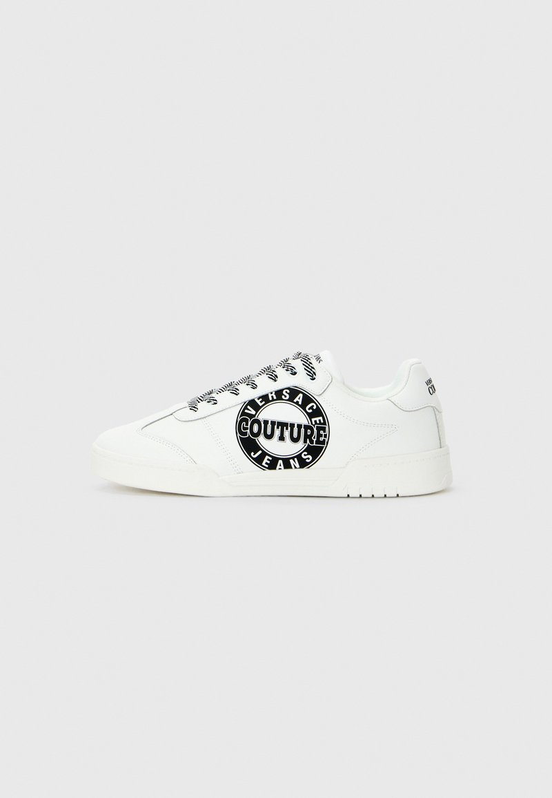Biele nízkoprofilové tenisky s čierno-bielymi šnúrkami a veľkým čiernym kruhovým logom "Versace Jeans Couture" na boku.