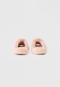 Lyserøde faux fur slippers med åben hæl og rund tådesign. Blød tekstur med en plush finish, der har en tyk, polstret sål.