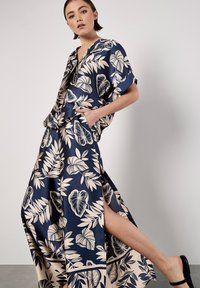 Conjunto de estampado floral en azul marino y beige que incluye una blusa holgada con escote en V y una falda a juego con una abertura lateral. Textura suave y sedosa.